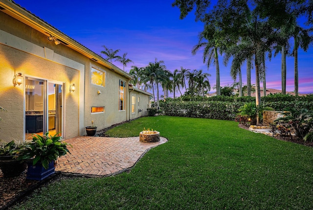 yard at dusk featuring an outdoor fire pit and a patio area