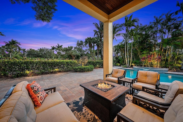 patio terrace at dusk featuring an in ground hot tub and an outdoor fire pit