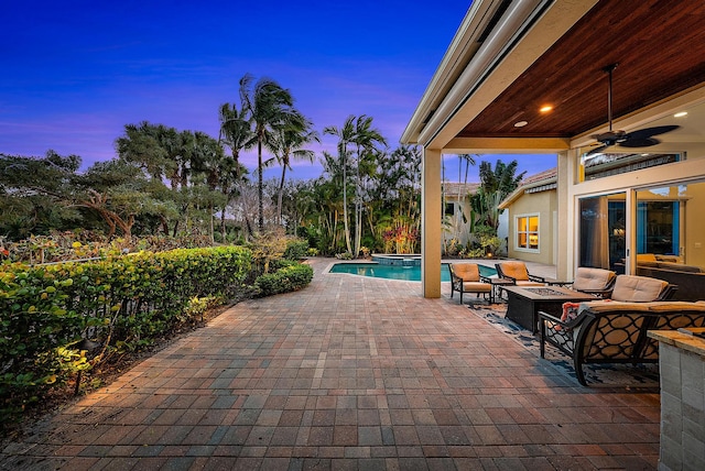 patio terrace at dusk with ceiling fan and an outdoor living space with a fire pit