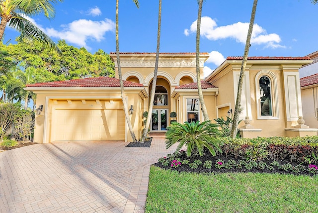 7190 Tradition Cove Ln E, West Palm Beach, FL 33412 - mediterranean / spanish house with stucco siding, a garage, decorative driveway, a tiled roof, and french doors
