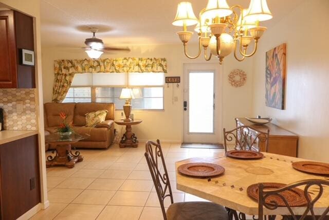 tiled dining space with ceiling fan with notable chandelier