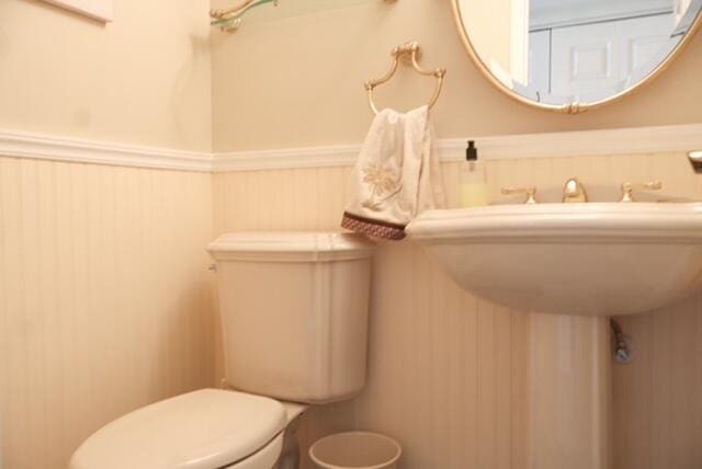 bathroom featuring toilet and wooden walls