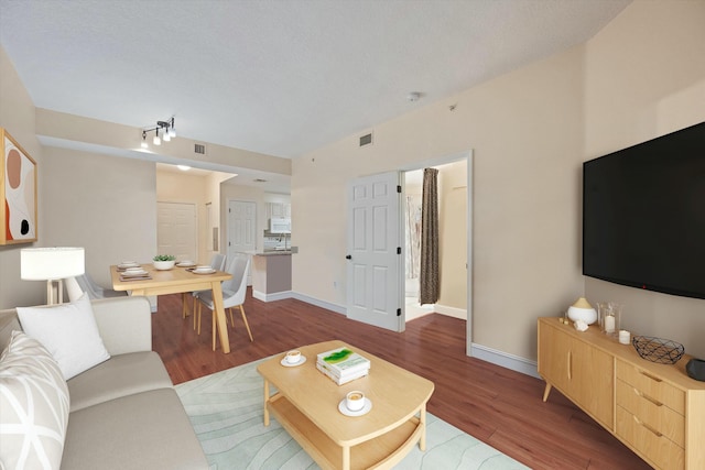 living area with wood finished floors, visible vents, and baseboards