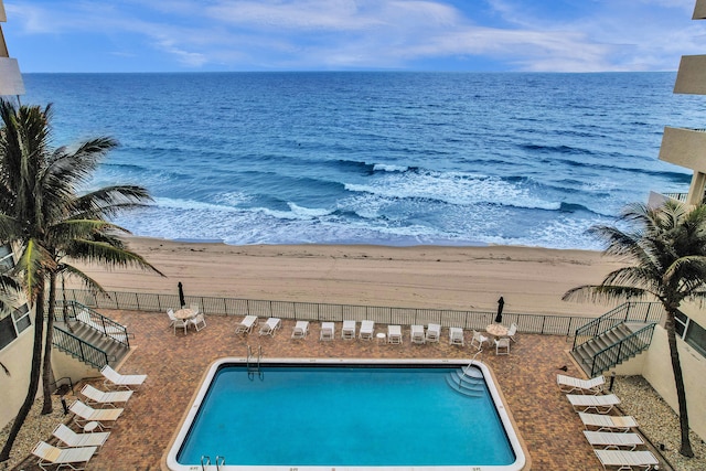 view of swimming pool with a water view and a view of the beach