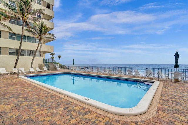 view of pool featuring a patio area and a water view