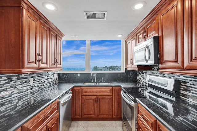 kitchen featuring decorative backsplash, sink, stainless steel appliances, and dark stone counters