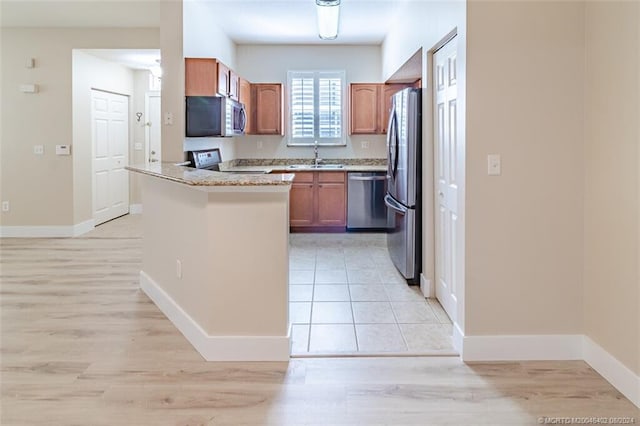 kitchen with kitchen peninsula, light hardwood / wood-style flooring, stainless steel appliances, and sink