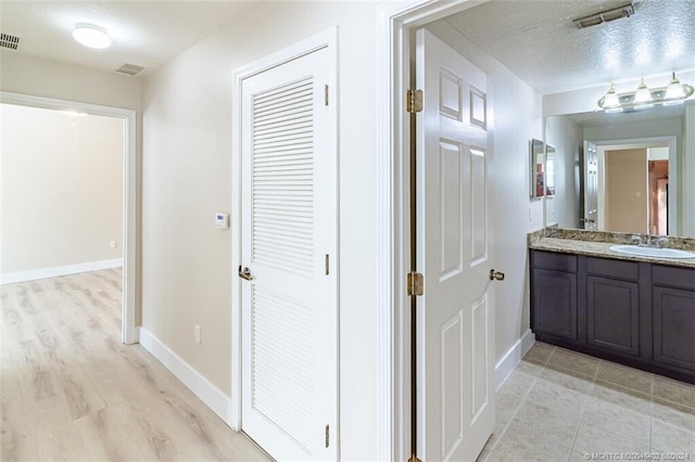 hallway with light hardwood / wood-style flooring, sink, and a textured ceiling