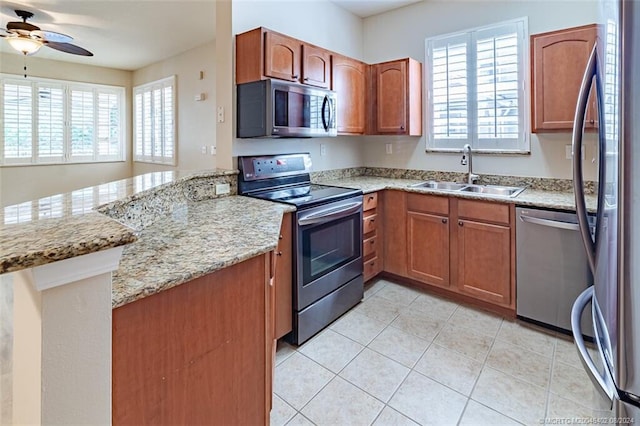 kitchen with sink, light tile patterned floors, kitchen peninsula, light stone countertops, and stainless steel appliances