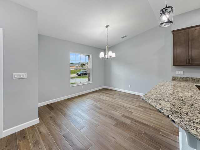 unfurnished dining area with a chandelier and light hardwood / wood-style flooring