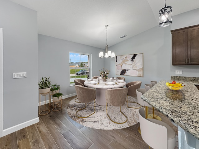 dining area with a chandelier, dark hardwood / wood-style flooring, and vaulted ceiling