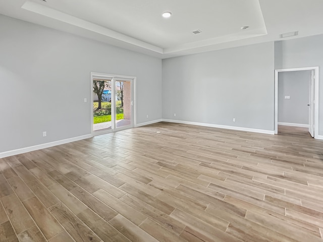 empty room with light hardwood / wood-style floors and a raised ceiling