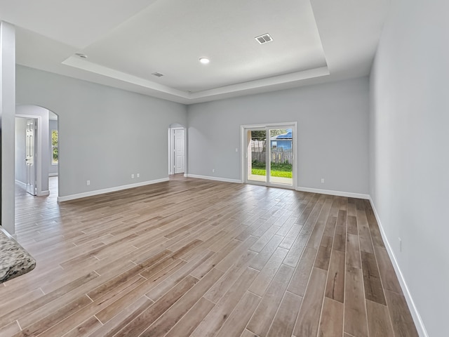 unfurnished room featuring a tray ceiling and light wood-type flooring