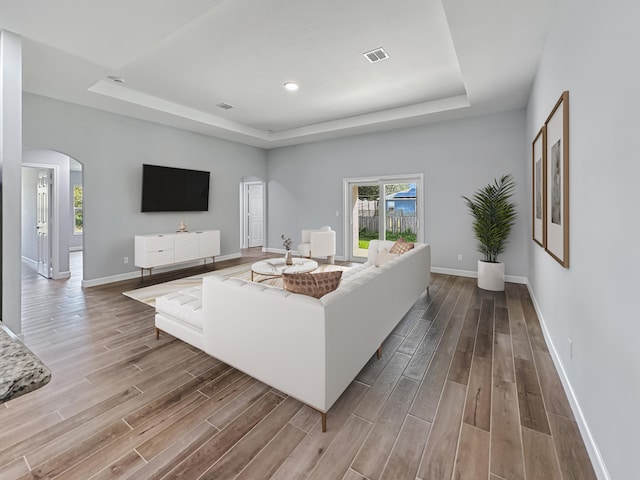 living room featuring light wood-type flooring and a tray ceiling