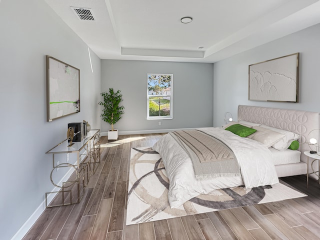 bedroom featuring a tray ceiling and wood-type flooring