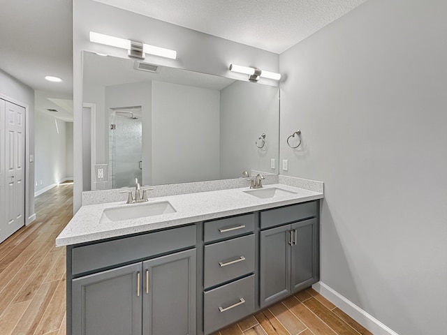 bathroom with hardwood / wood-style flooring, vanity, a shower with door, and a textured ceiling