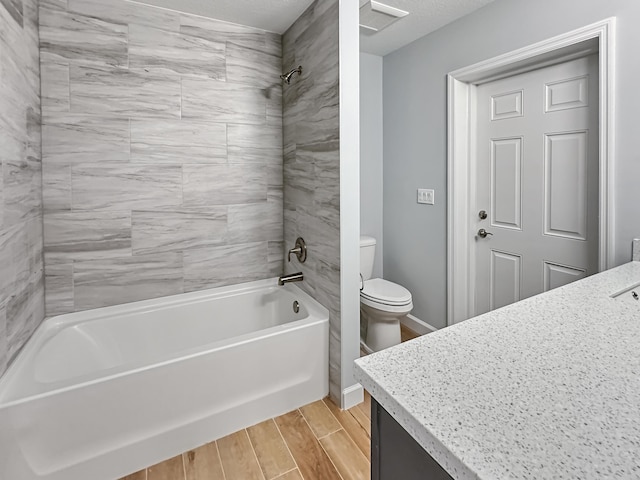 full bathroom with a textured ceiling, vanity, tiled shower / bath combo, hardwood / wood-style flooring, and toilet