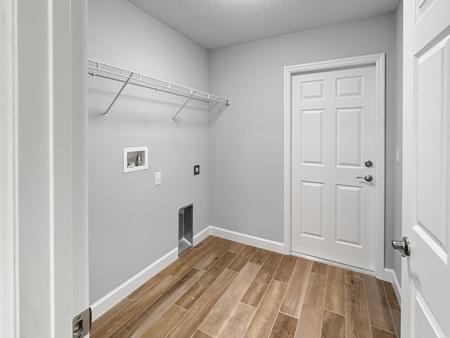 laundry room with hookup for an electric dryer, washer hookup, a textured ceiling, and hardwood / wood-style flooring