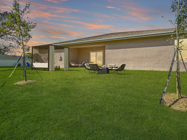 back house at dusk with a lawn and an outdoor hangout area