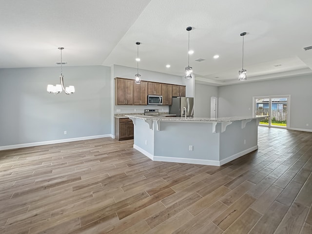 kitchen featuring pendant lighting, a breakfast bar, hardwood / wood-style flooring, a large island, and stainless steel appliances