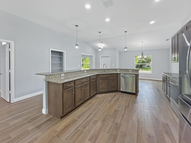 kitchen featuring pendant lighting, a center island with sink, vaulted ceiling, light hardwood / wood-style floors, and stainless steel appliances