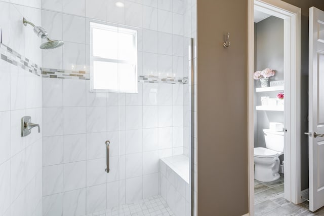 bathroom featuring a shower with shower door and toilet