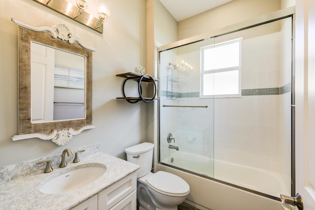 full bathroom featuring toilet, vanity, and shower / bath combination with glass door