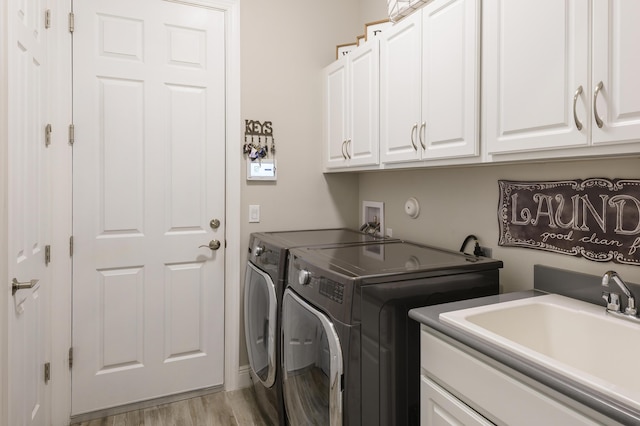 laundry room featuring cabinets, sink, independent washer and dryer, and light wood-type flooring