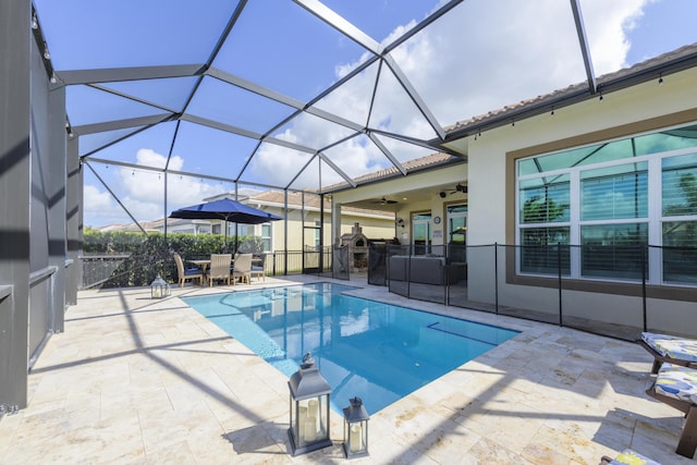 view of swimming pool with a patio, ceiling fan, and glass enclosure