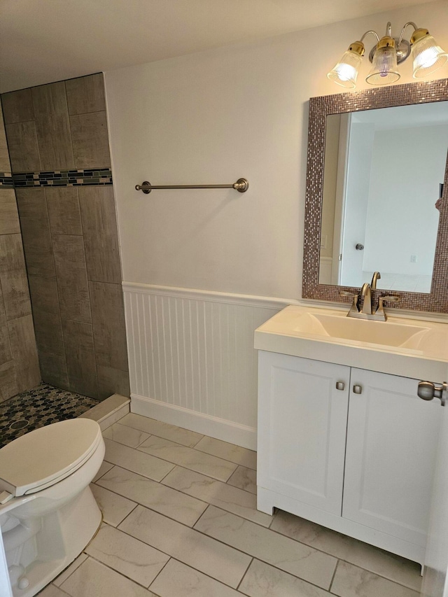 bathroom featuring a tile shower, tile patterned floors, vanity, and toilet