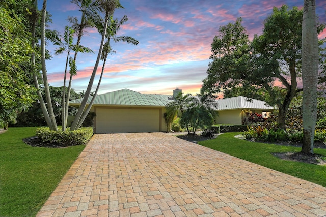 single story home featuring a lawn and a garage