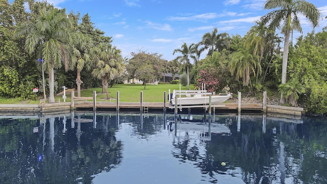 view of dock featuring a lawn and a water view