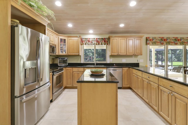 kitchen featuring a center island, dark stone counters, sink, appliances with stainless steel finishes, and light tile patterned flooring