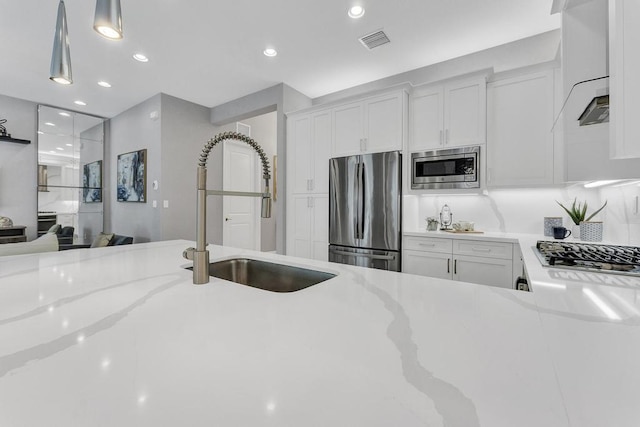 kitchen with appliances with stainless steel finishes, decorative light fixtures, white cabinetry, and sink