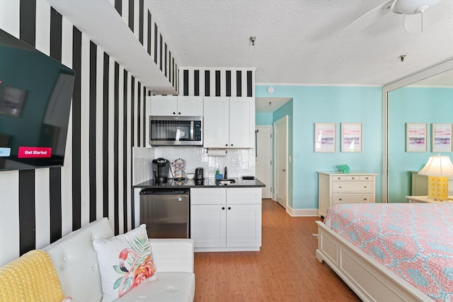 bedroom with a textured ceiling, light hardwood / wood-style floors, and ceiling fan