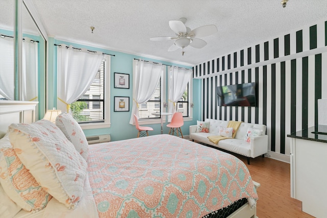 bedroom with ceiling fan, wood-type flooring, and a textured ceiling