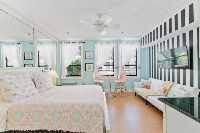 bedroom with light hardwood / wood-style flooring, ceiling fan, multiple windows, and a textured ceiling