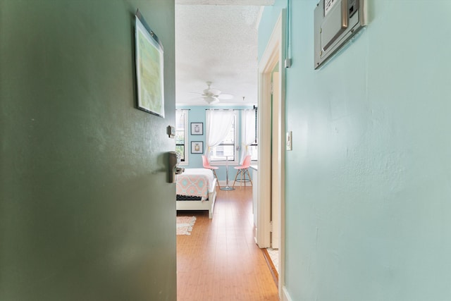 corridor with a textured ceiling and light wood-type flooring