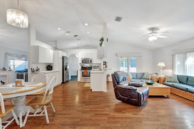 living room with ceiling fan with notable chandelier, a healthy amount of sunlight, lofted ceiling, and wood-type flooring