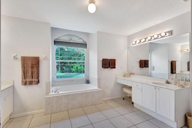 bathroom with tile patterned flooring, a relaxing tiled tub, a textured ceiling, and vanity