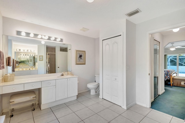 bathroom with a textured ceiling, vanity, ceiling fan, tile patterned flooring, and toilet