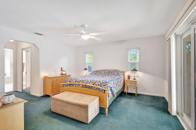 bedroom with dark colored carpet, a textured ceiling, and ceiling fan