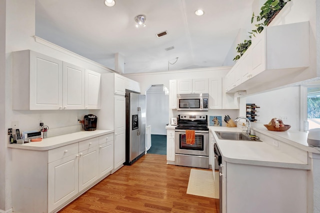 kitchen featuring white cabinets, stainless steel appliances, vaulted ceiling, and sink