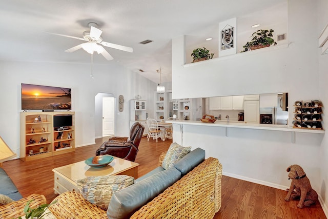 living room featuring ceiling fan, hardwood / wood-style floors, and vaulted ceiling