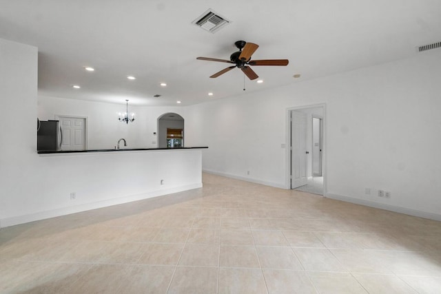 unfurnished living room featuring sink, light tile patterned floors, and ceiling fan with notable chandelier