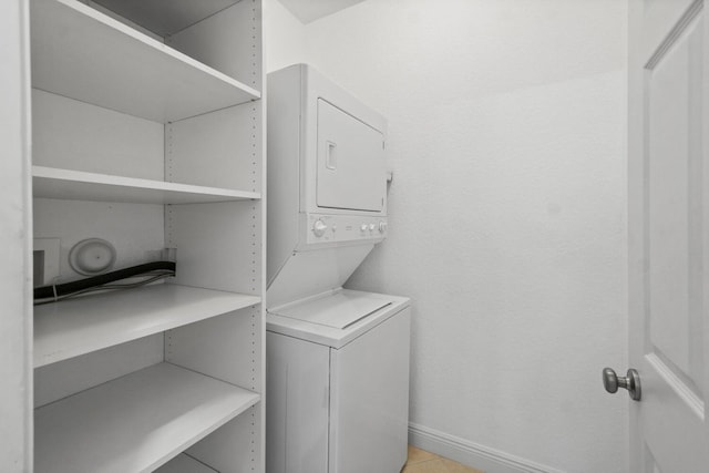 washroom with stacked washer / drying machine and light tile patterned flooring