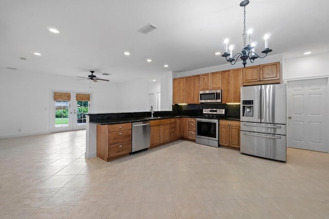 kitchen with sink, stainless steel appliances, backsplash, kitchen peninsula, and decorative light fixtures