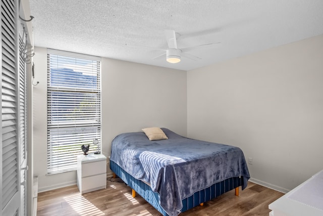 bedroom with ceiling fan, wood-type flooring, and a textured ceiling