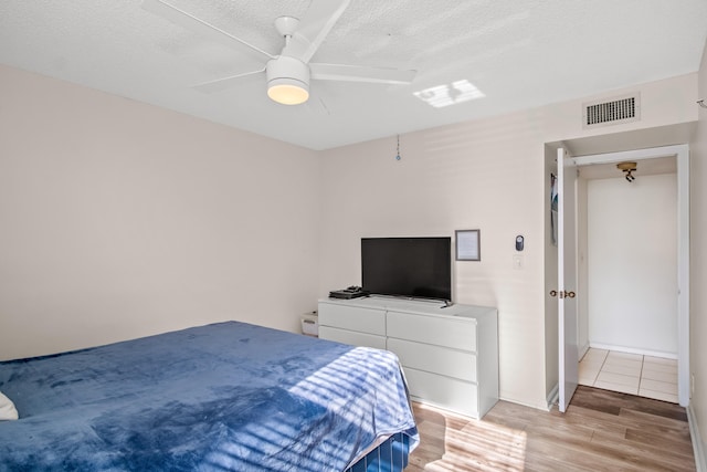 bedroom featuring ceiling fan, light hardwood / wood-style flooring, and a textured ceiling