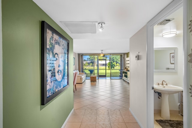 corridor featuring light tile patterned floors, a wall of windows, and sink